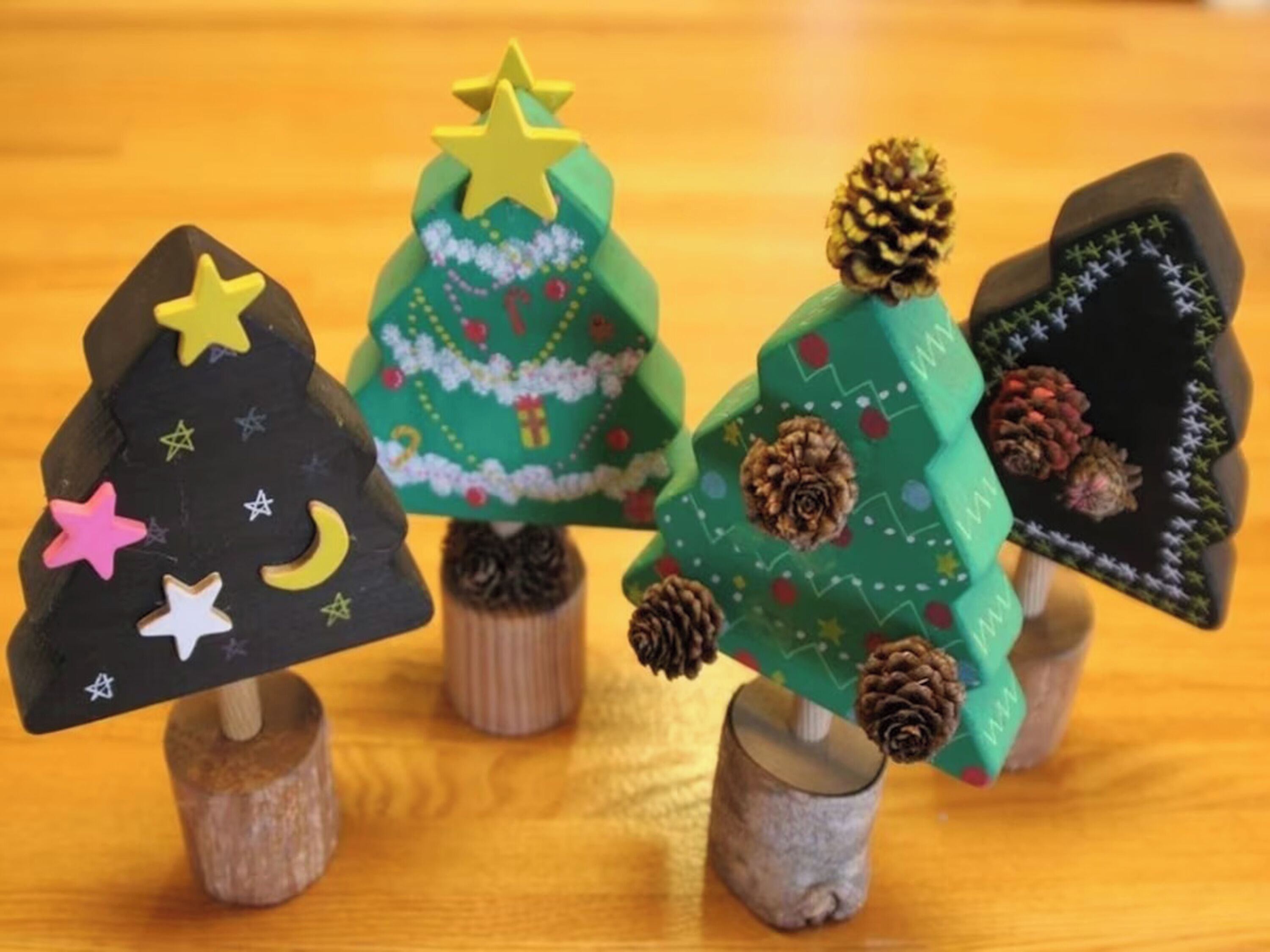 Quatre petits sapins de Noël, présentés sur des supports en bois.