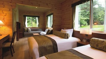 Een kamer in chaletstijl met twee bedden, een bureau en een raam met uitzicht op bomen.