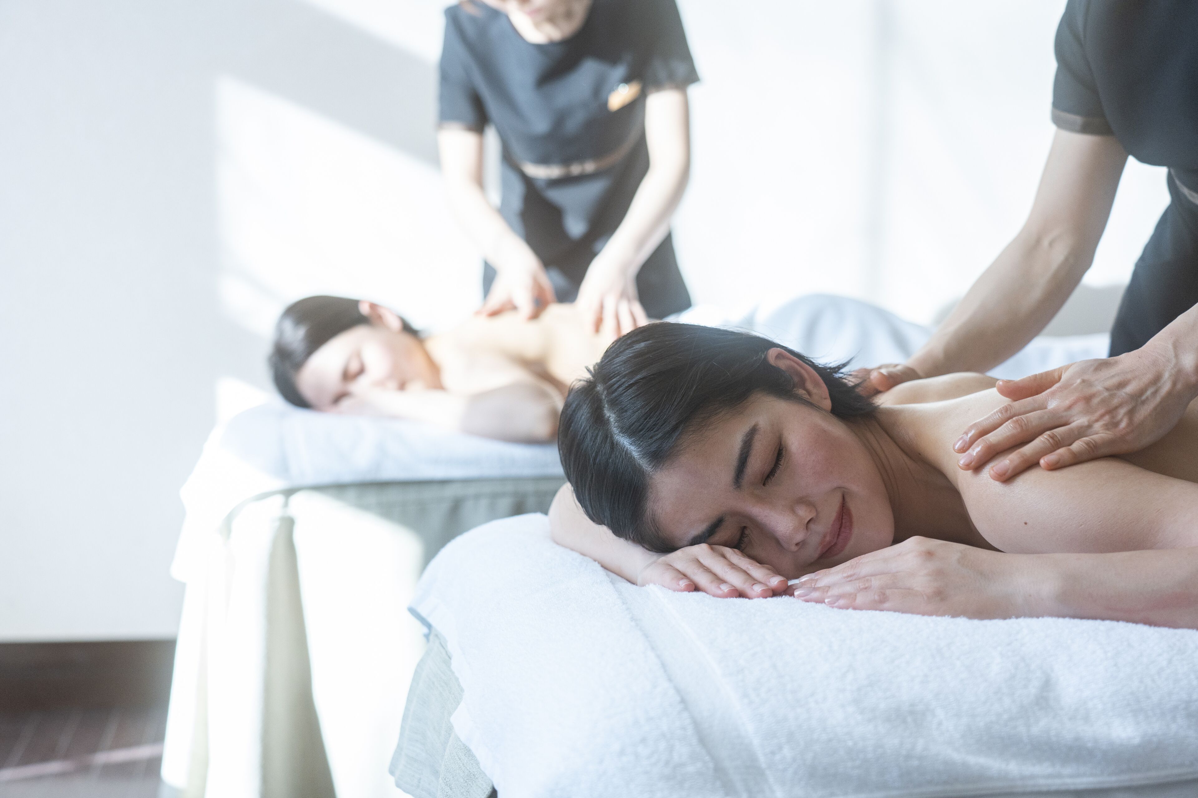 Una sesión de masoterapia en una habitación con una cama y una mesa de masaje.