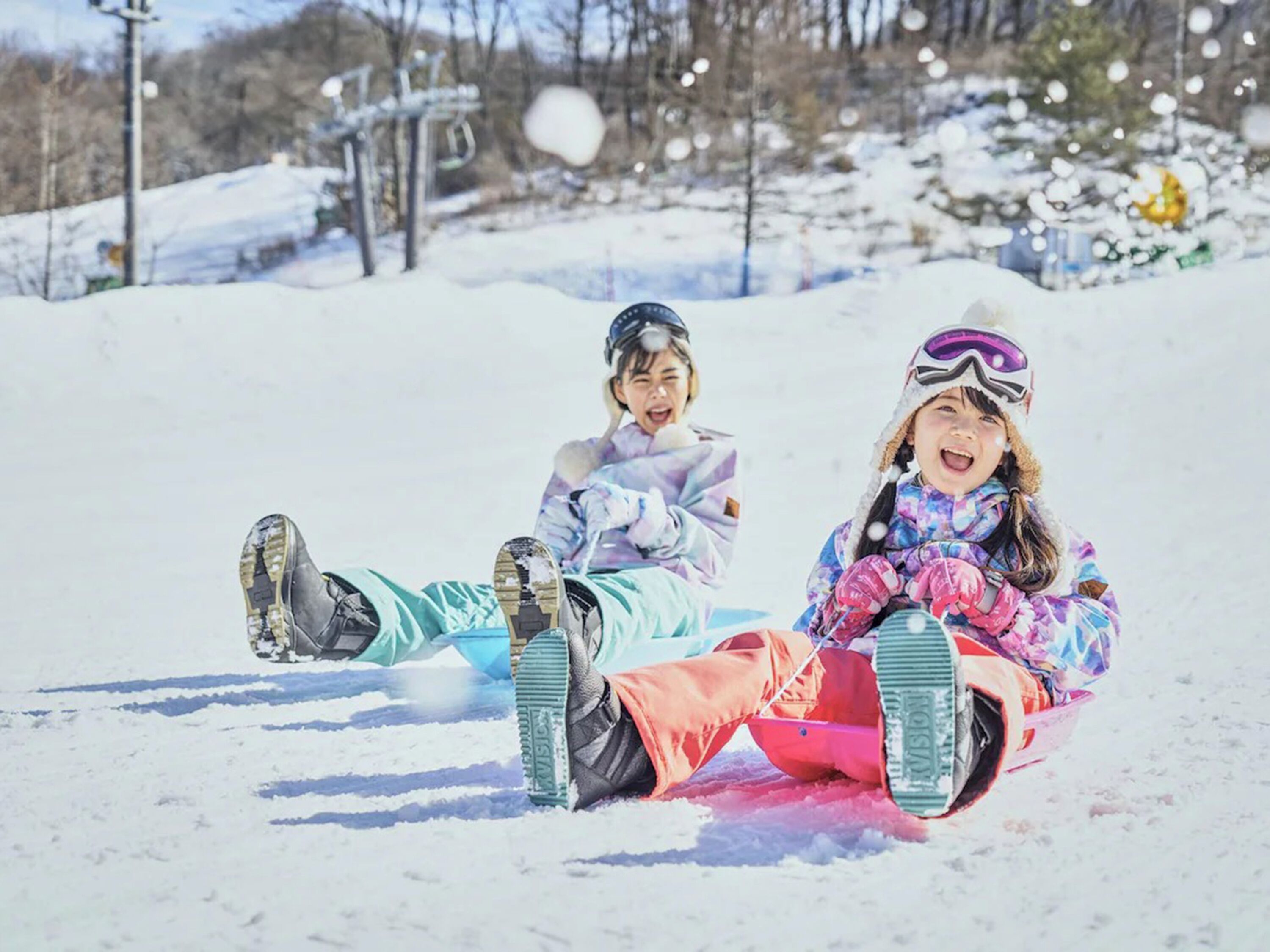 Dos niños deslizando un trineo por una pendiente nevada.