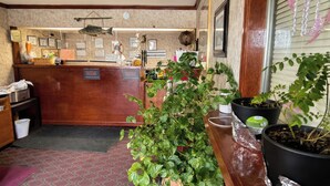 A reception area with a wooden counter, a welcome sign, framed certificates, and potted plants. - Lake Erie Lodge Oregon OH (Curtice)