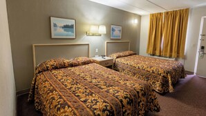 A hotel room with two beds, a nightstand, a lamp, and a window with curtains. - Lake Erie Lodge Oregon OH (Curtice)