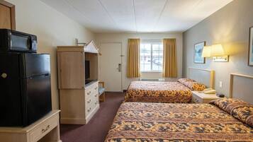 A hotel room with two beds, a refrigerator, a TV, a desk, and a window with curtains.