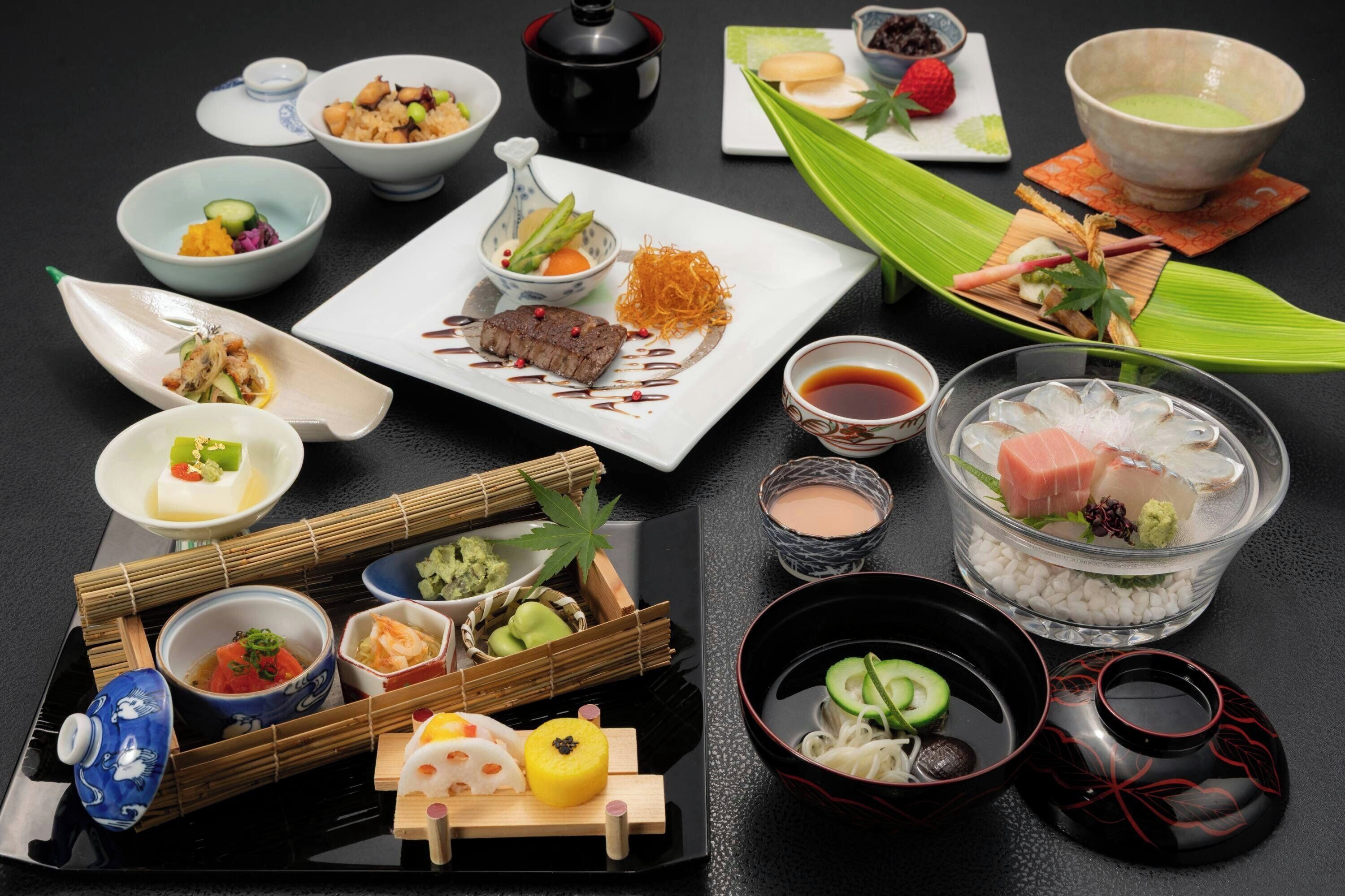 A variety of dishes and beverages arranged on a table, including sushi, sashimi, and a teapot.