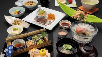 A variety of dishes and beverages arranged on a table, including sushi, sashimi, and a teapot.