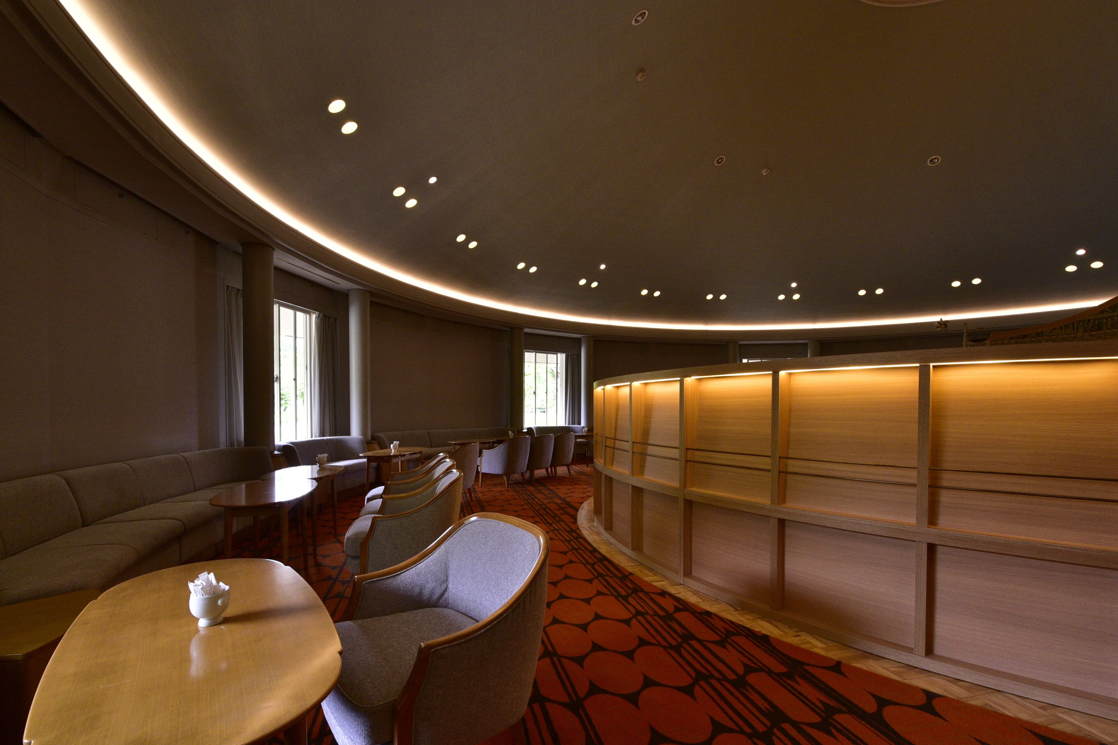 A hotel lobby with a curved ceiling, seating area, and a reception desk.