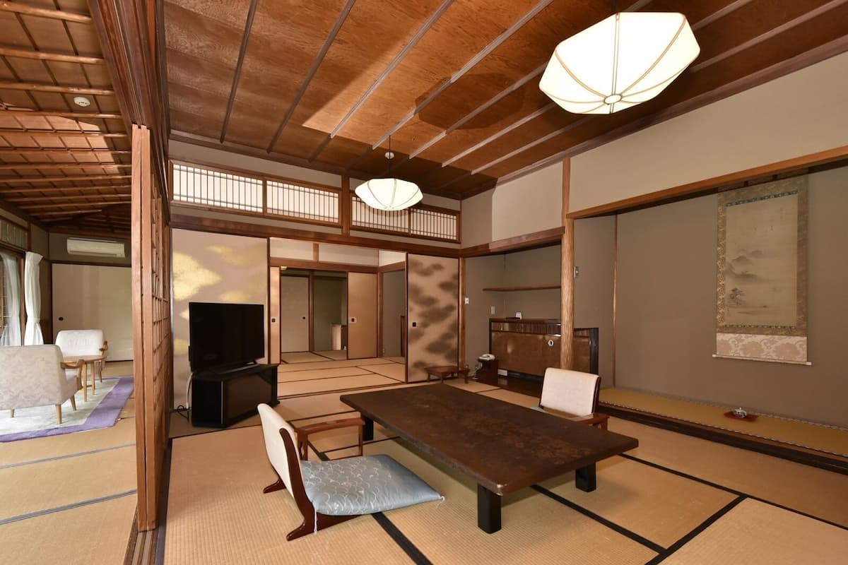 A traditional Japanese room with tatami flooring, a low table, and a television.