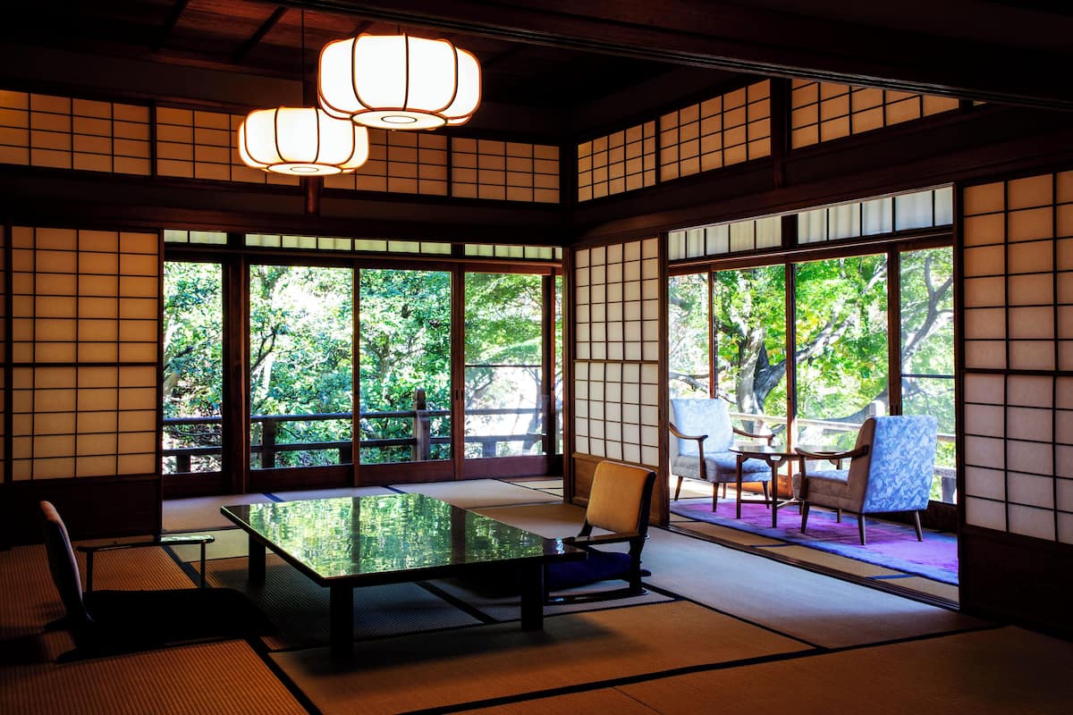 A traditional Japanese room with tatami flooring, shoji screens, and a low table with chairs.