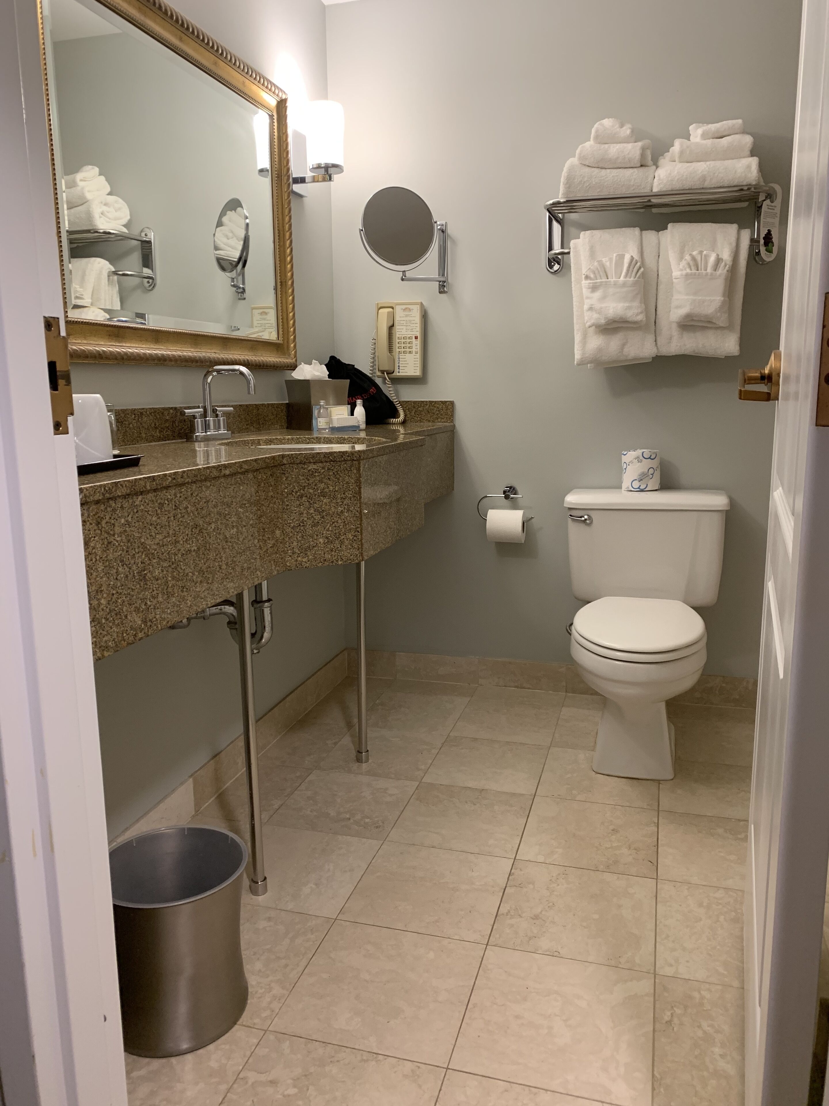 A bathroom with a granite sink, a mirror, a toilet, and a towel rack.