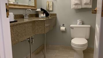 A bathroom with a granite sink, a mirror, a toilet, and a towel rack.