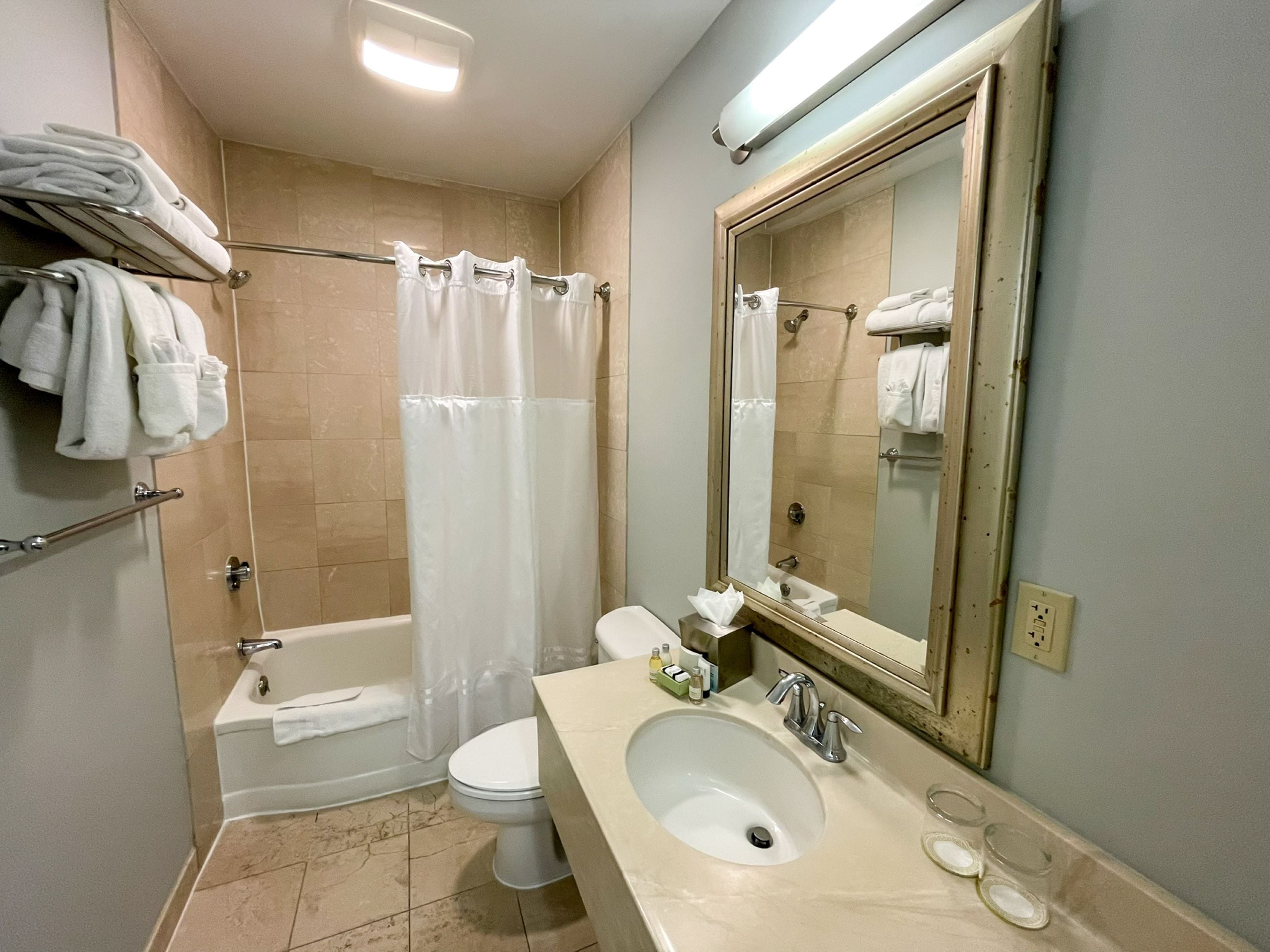 A bathroom with a bathtub, toilet, sink, and a large mirror.