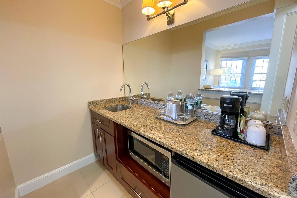 A kitchen with granite countertops, a double sink, a microwave, a coffee maker, and a toaster.