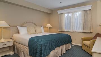 A hotel room with a bed, two bedside tables, a chair, and a window with curtains.