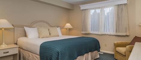 A hotel room with a bed, two bedside tables, a chair, and a window with curtains.