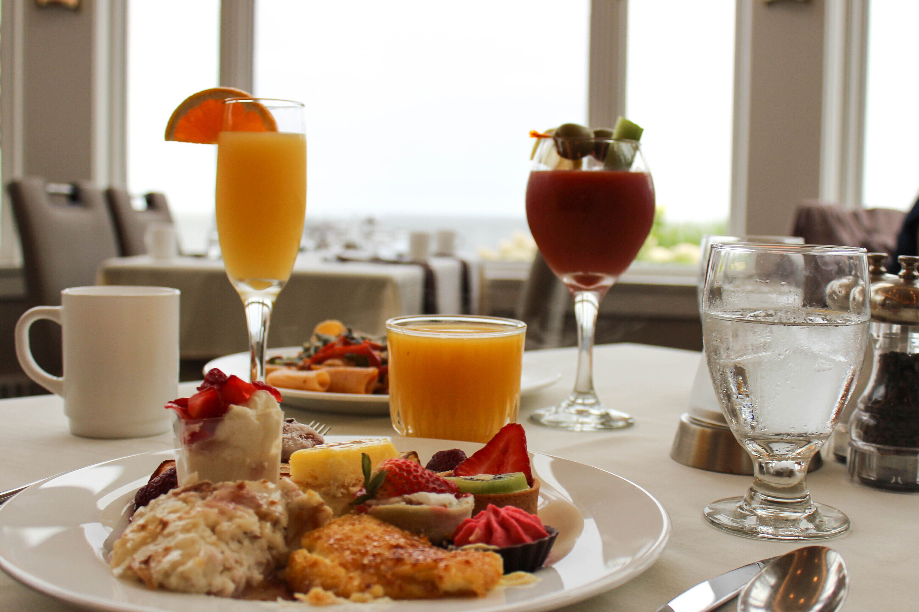 A breakfast setting with a variety of dishes, drinks, and a view of the outdoors.