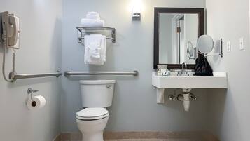 Un baño moderno con inodoro, baranda, toallero, lavamanos con espejo y teléfono.