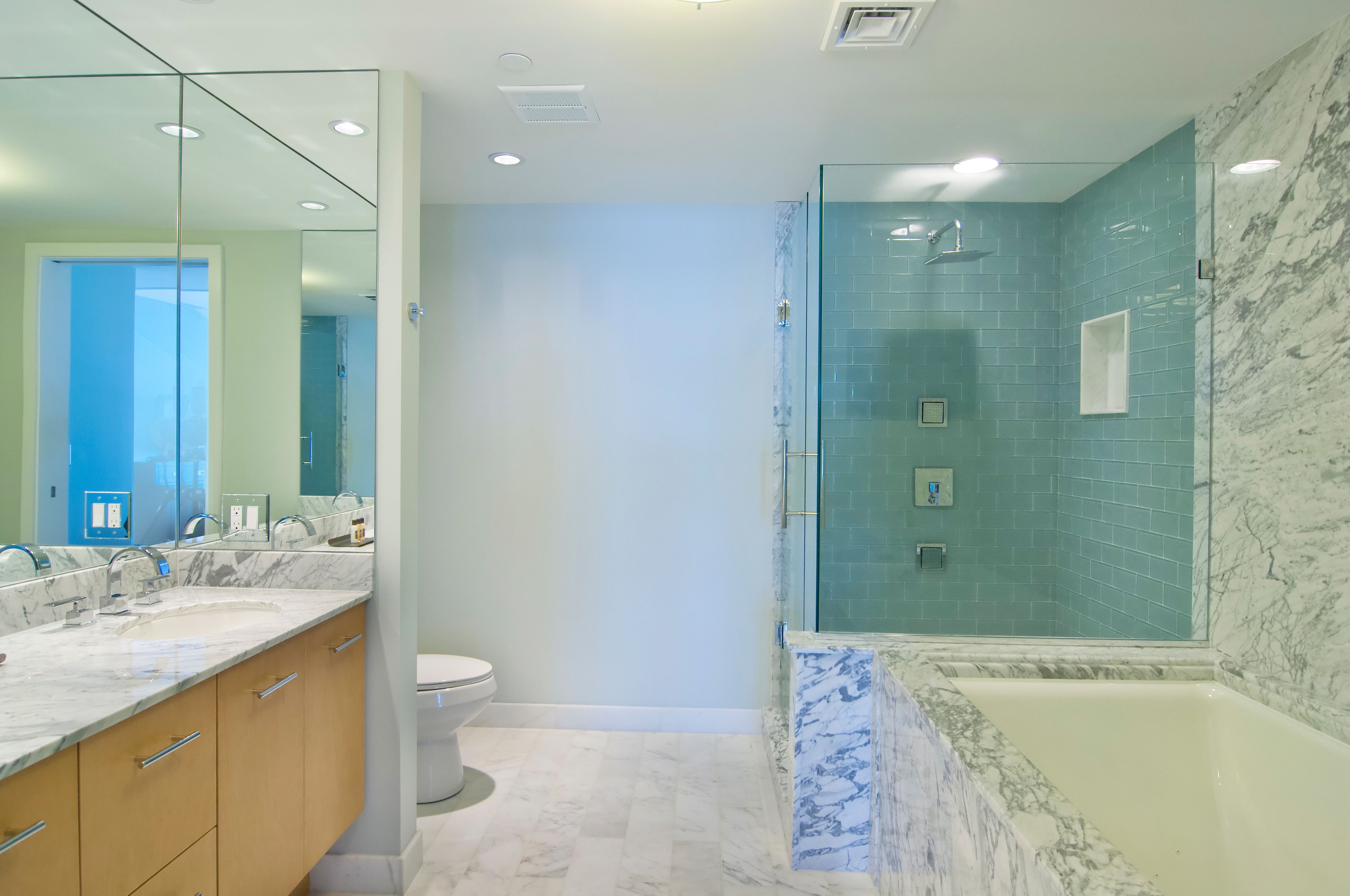 A modern bathroom with a marble vanity, a glass shower enclosure, and a bathtub.