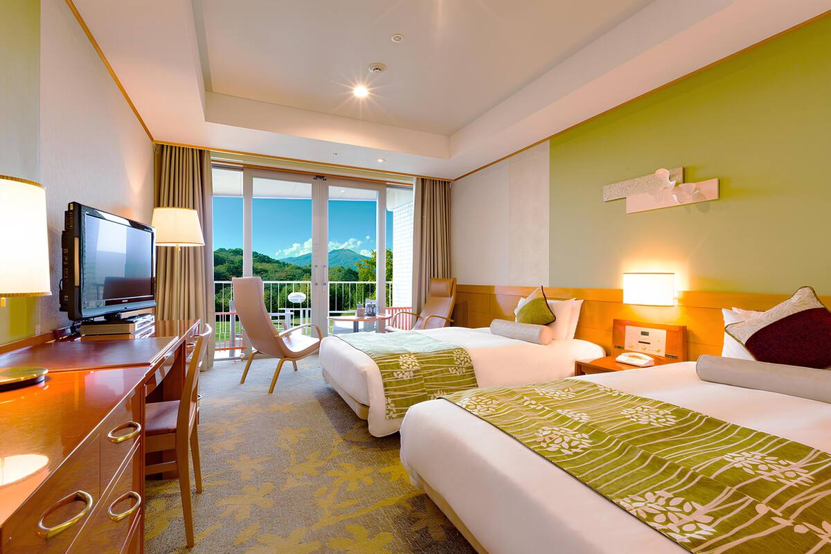 A hotel room with a TV, two beds, a desk, and a chair.