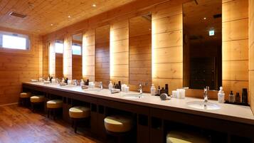 Un baño espacioso con acabados de madera, varios lavamanos y taburetes.