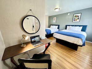 A hotel room with a desk, laptop, two beds, and a round mirror. - Ashland Motel - Oregon (Ashland)