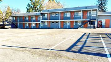 A motel with multiple rooms, a parking lot, and a staircase leading to the entrance.
