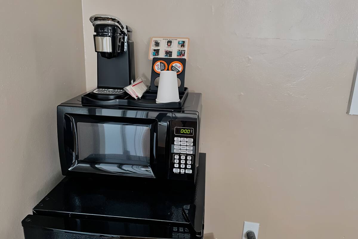Une machine à café dotée d’un écran numérique, une cafetière, une tasse et une dosette de café.