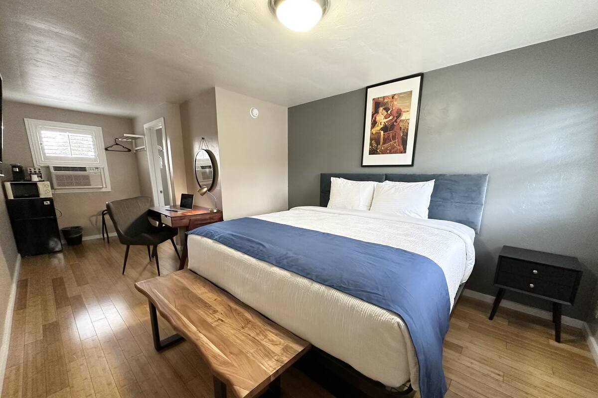 Une chambre bien rangée, avec un lit, une table de chevet et un bureau avec une chaise.