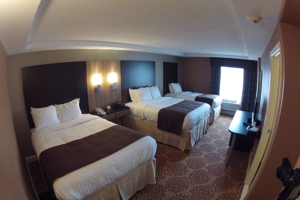 Een hotelkamer met twee bedden, een bureau en een raam.