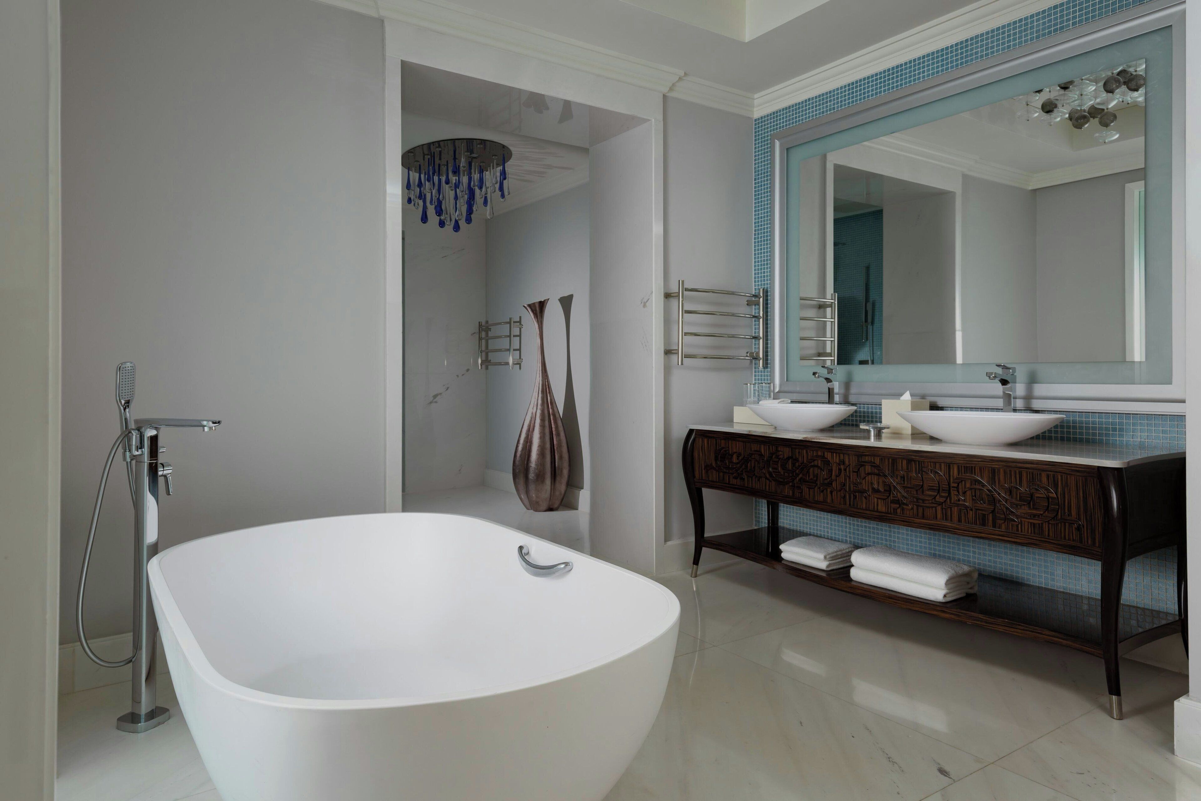 A modern bathroom with a freestanding bathtub, a large mirror, and a vanity with two sinks.
