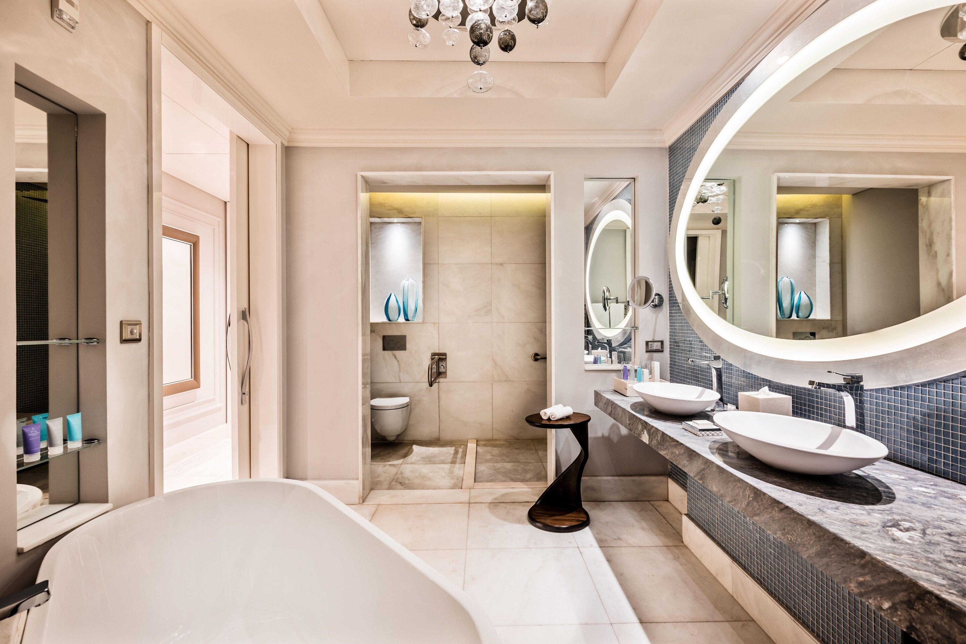 A modern bathroom with a bathtub, two sinks, a vanity, and a large mirror.