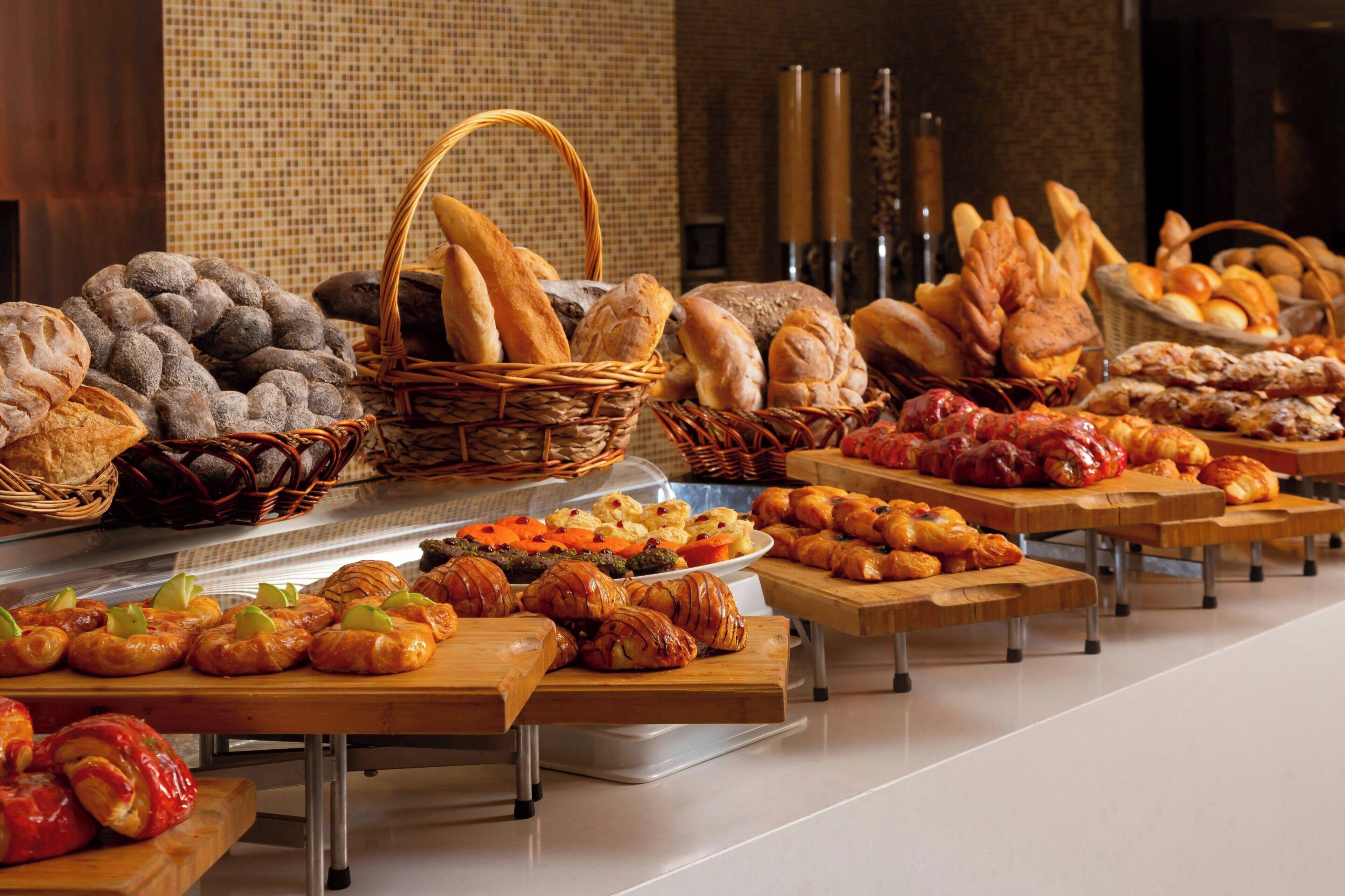 A buffet with various breads, pastries, and desserts.