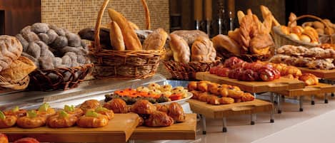 A buffet with various breads, pastries, and desserts.
