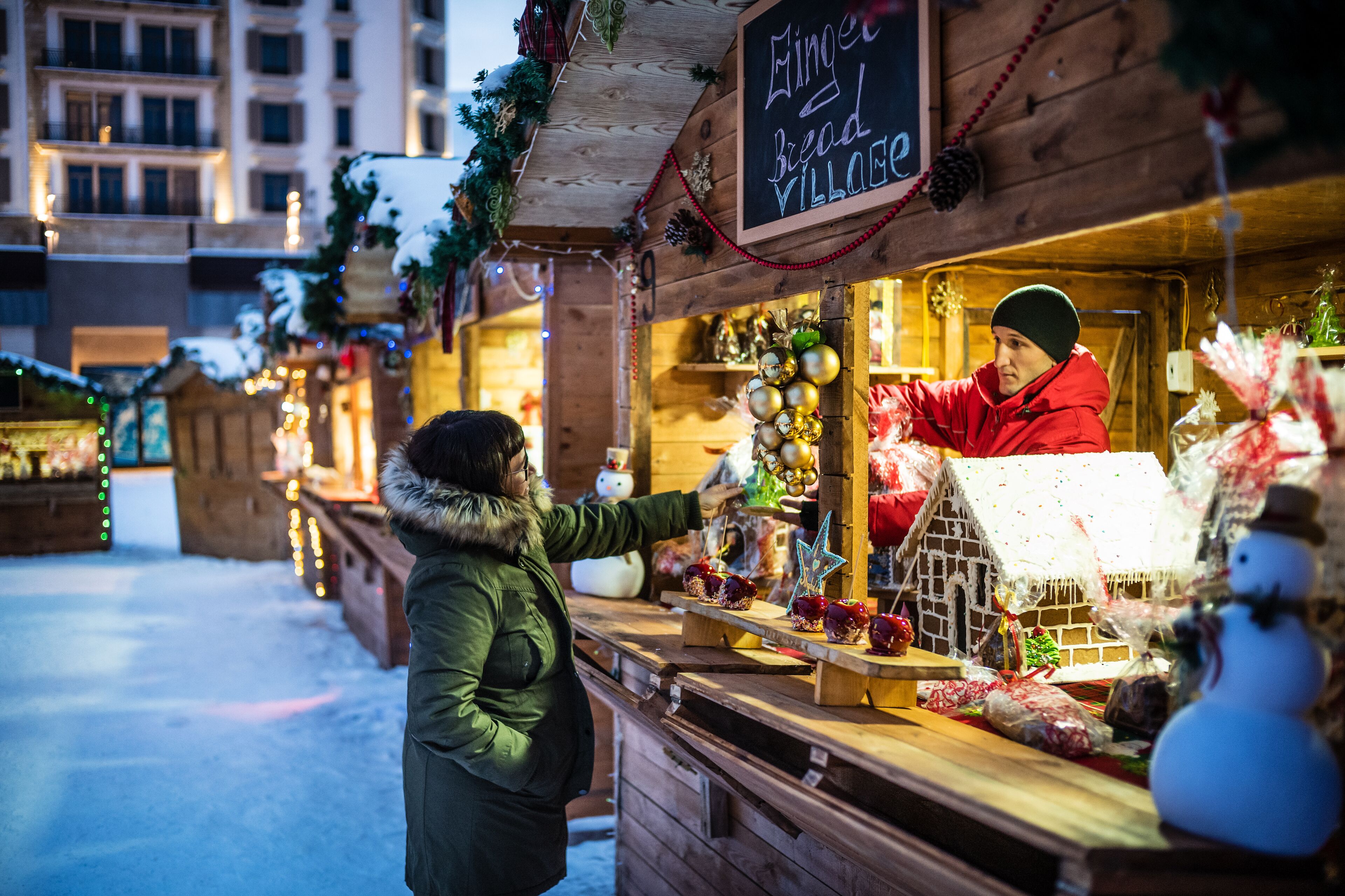 A gingerbread village stall with a sign, decorated with ornaments and gingerbread houses.