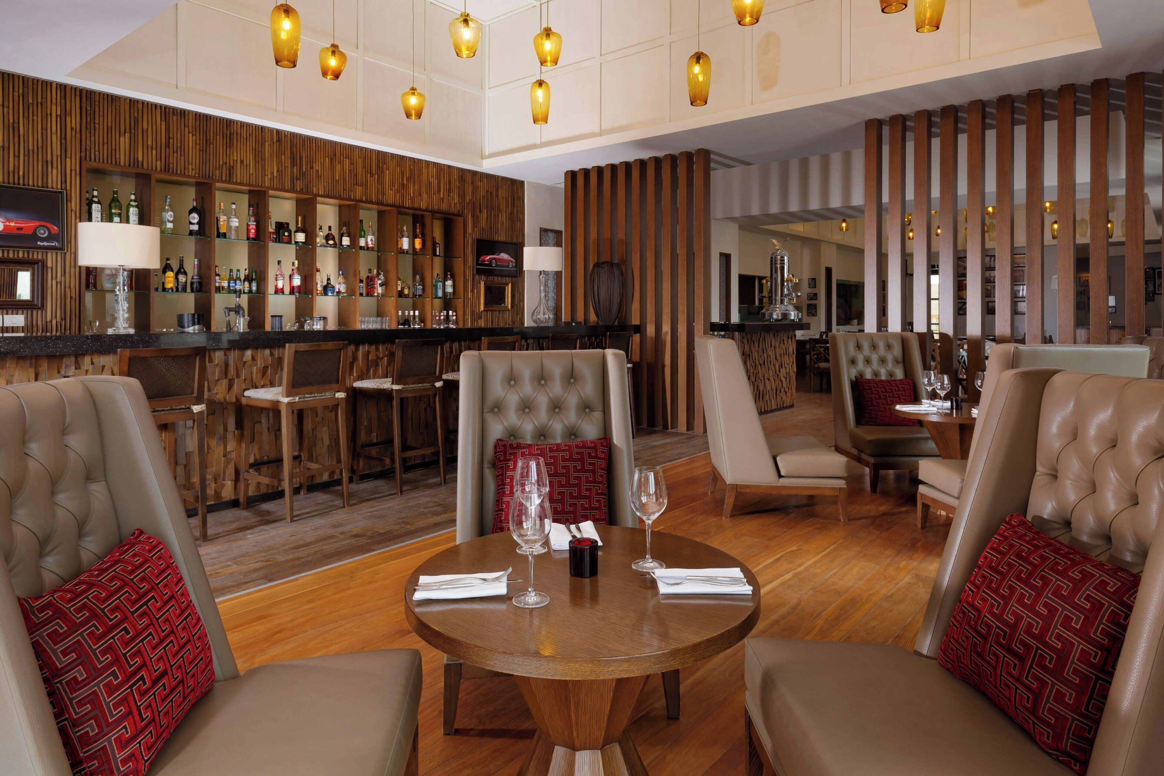 A spacious lounge area with leather sofas, a wooden bar with a variety of bottles, and a television screen.