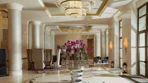 A spacious lobby with a grand chandelier, marble columns, and a central floral arrangement. - Pik Palace, Shahdag, Autograph Collection (Qusar)