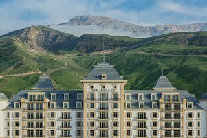 A large building with the sign "Pik Palace" on the front, surrounded by green hills and mountains.