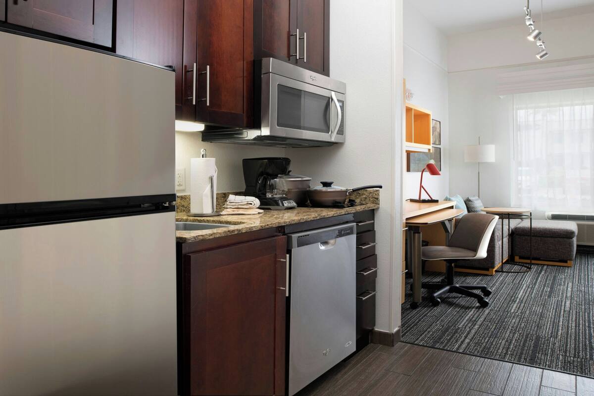 Una cocina compacta equipada con microondas, lavavajillas y un pequeño comedor con una mesa y una silla.