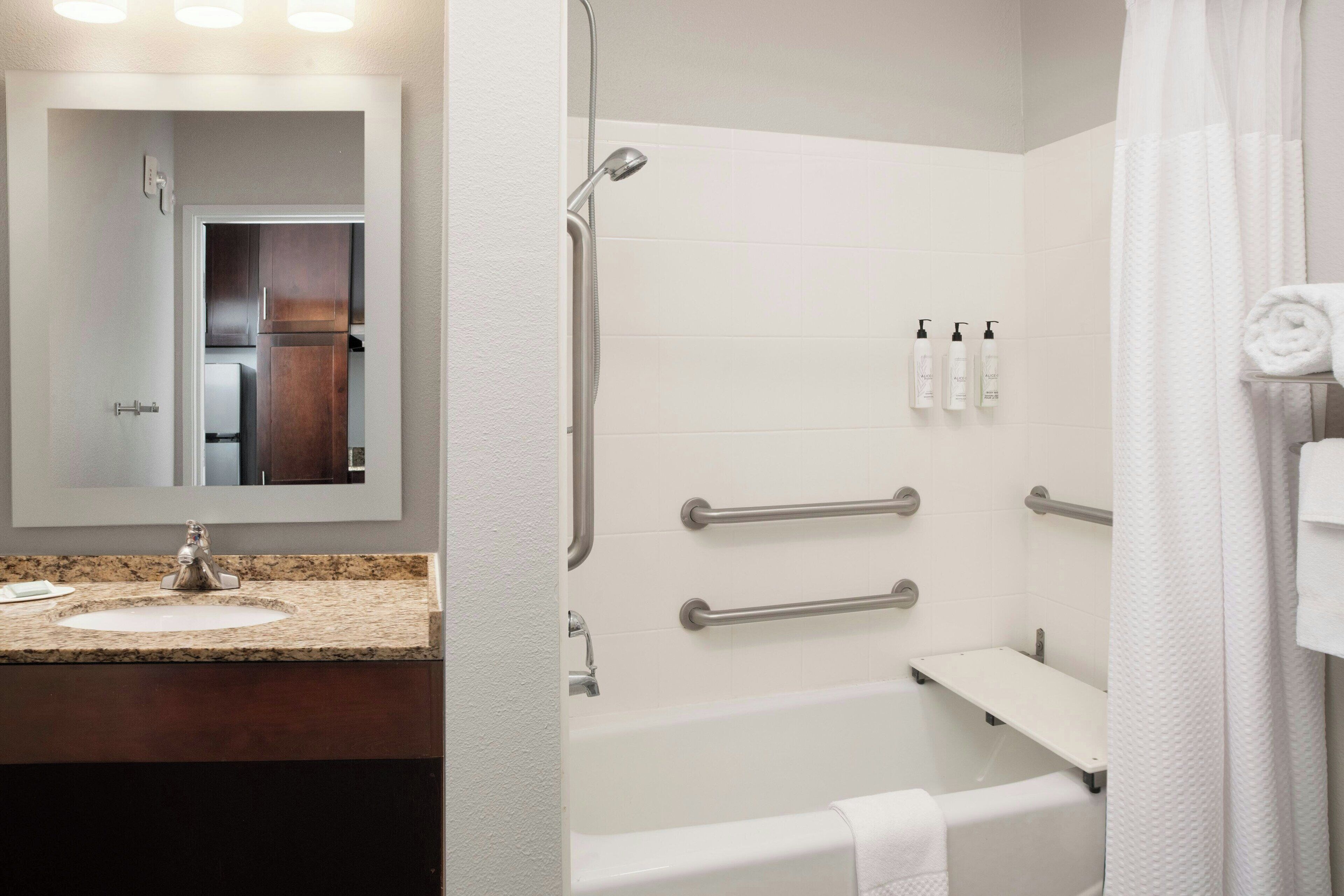 Une salle de bain moderne équipée d’un lavabo, d’un miroir, d’une douche et de toilettes.