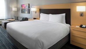 A hotel room with a large bed, a bedside table with a lamp, a chair, a desk, and a wall-mounted phone. - TownePlace Suites by Marriott Laredo (Laredo)