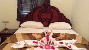A neatly made bed with a heart-shaped towel arrangement and flowers on a quilted bedspread. - Adam Suites (Santo Domingo)
