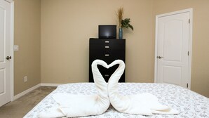 A bedroom with a bed, a dresser, and a TV on top.