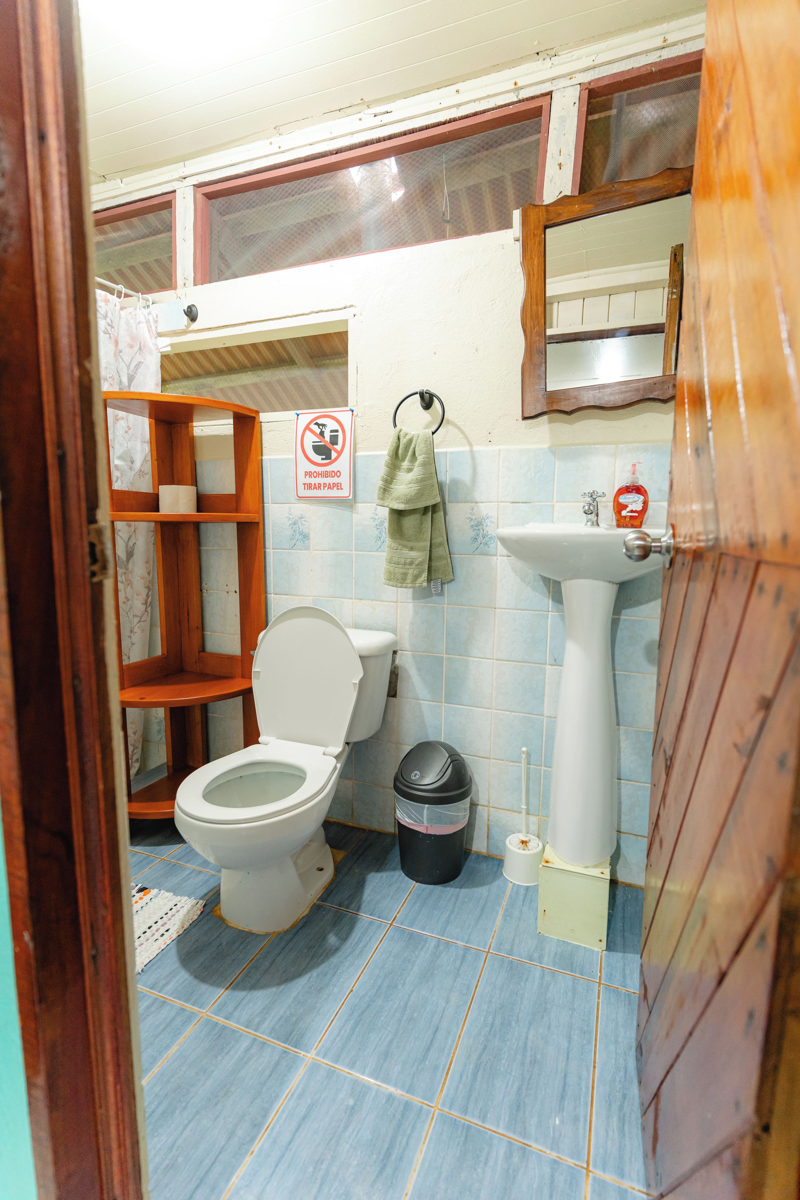A bathroom with a toilet, sink, and a trash bin.