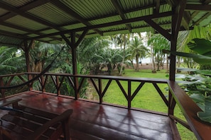 Une terrasse en bois couverte, offrant une vue sur un jardin tropical.