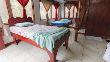 A bedroom with a wooden bed, a small bedside table, and a window with curtains.