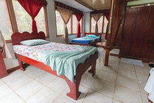 Un dormitorio con una cama de madera, una mesita de noche pequeña y una ventana con cortinas.