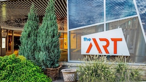 Une entrée avec une enseigne indiquant « THE ART » et une façade de bâtiment moderne.