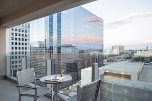 A modern hotel balcony with a glass railing, offering a view of a cityscape and a sunset. - The Art Hotel Denver, Curio Collection by Hilton (Denver)