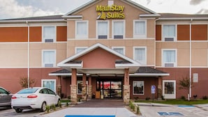 Ein Hotel mit einem Schild 'Maine Stay Suites', einem überdachten Eingang und einem Parkplatz für Menschen mit Behinderung.