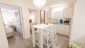 A modern kitchen with white cabinetry, a white dining table, and a chandelier. - Siesta Key Beachside Villas (Siesta Key)