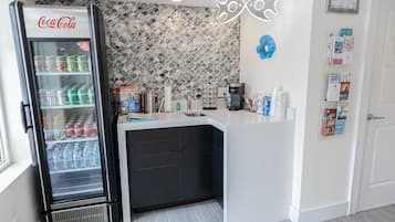 Una cocina con un refrigerador Coca-Cola, una cafetera y un salpicadero de azulejos.